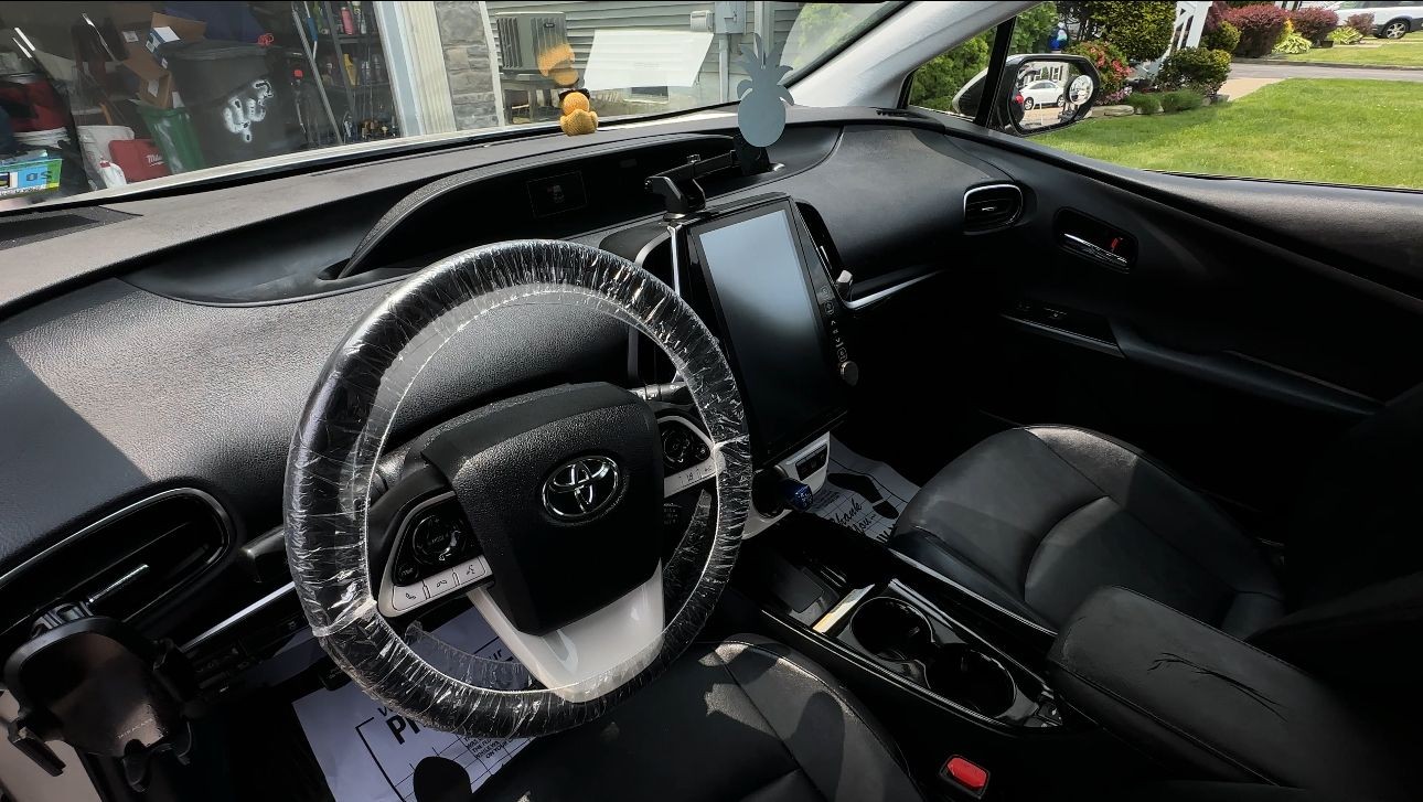 Interior of a modern car with a plastic-covered steering wheel and large touchscreen display.